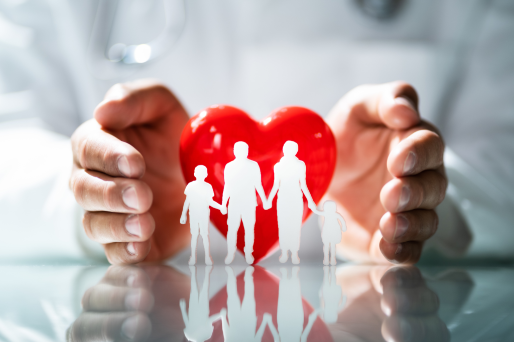 Hands gently holding a red heart shape with a family silhouette symbolizing health protection and care.