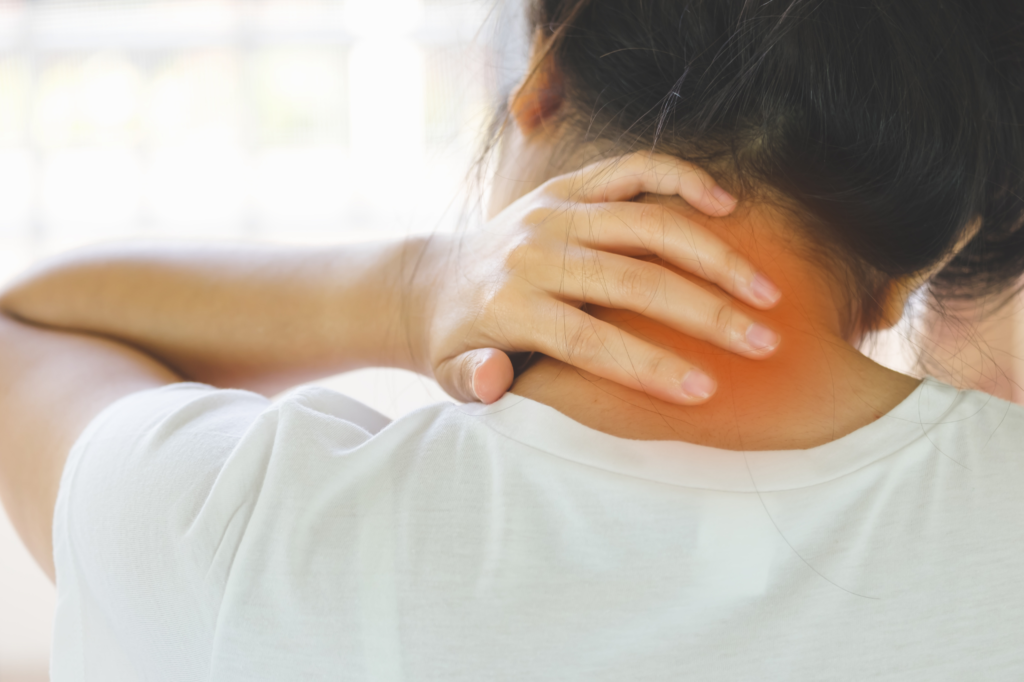 Person holding the back of their neck, indicating pain or stiffness in the cervical area.